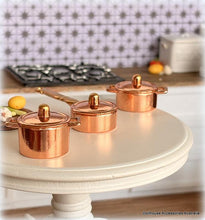 Set of copper pots with lids on a kitchen counter
