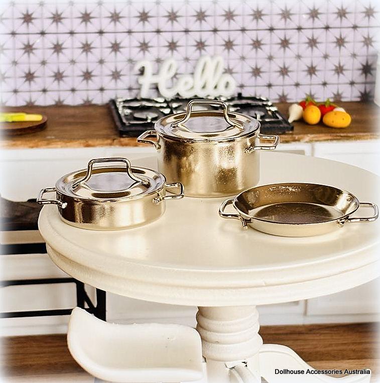 Set of silver-colored cookware on a white table with a kitchen background.
