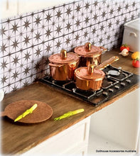 Copper pots on a miniature stove with decorative tiles in the background
