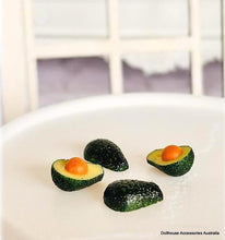 Miniature avocado slices with an orange center on a white surface
