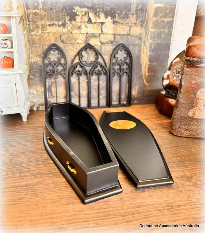 Black coffin with gold accents on a wooden surface, styled against a rustic background.