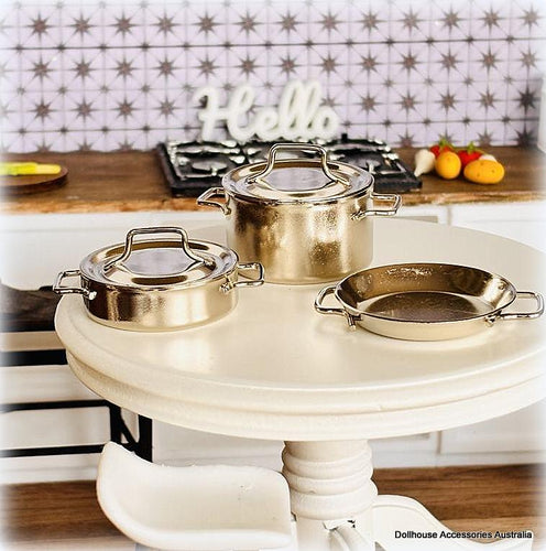 Set of silver-colored cookware on a white table with a kitchen background.