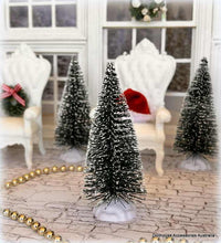 Miniature Christmas trees with snow effects in a decorative setting.