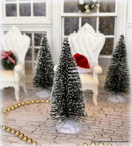 Miniature Christmas trees with snow effects in a decorative setting.