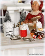 Dollhouse kitchen scene with miniature utensils, ingredients, and a figurine.